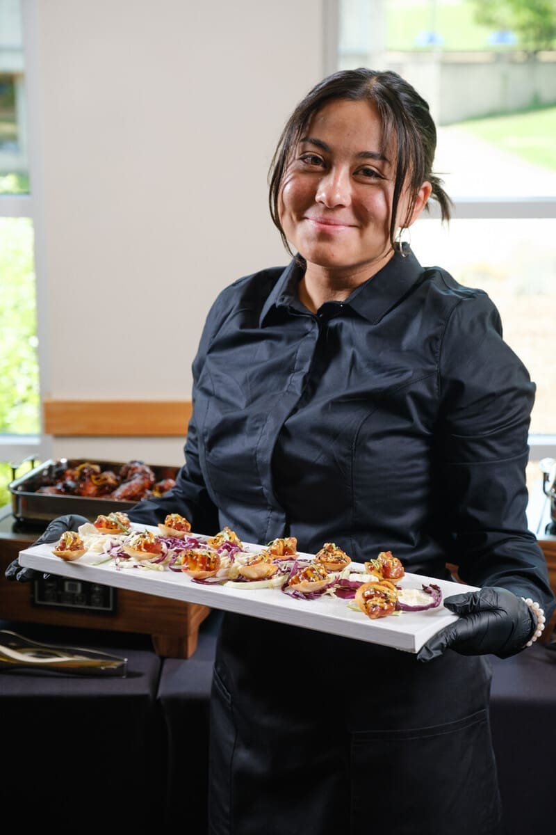 Two people grabbing food from catered buffet